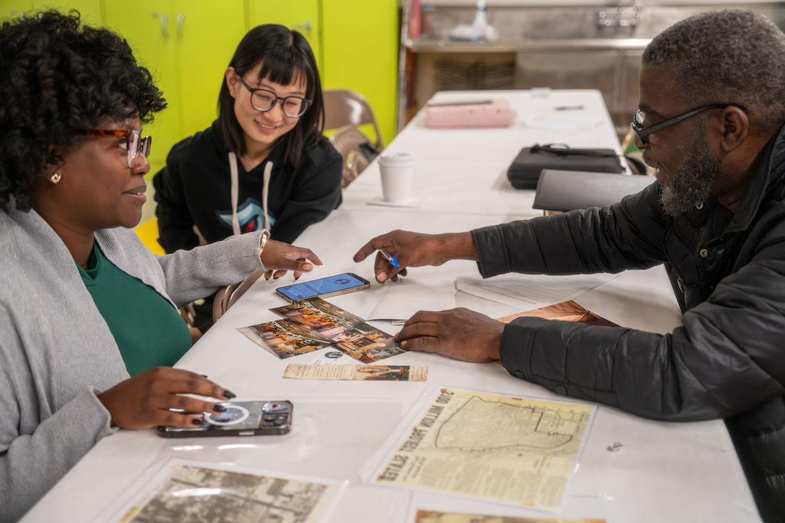 Syracuse University volunteers work with woman to scan photos as part of the Family Pictures program.